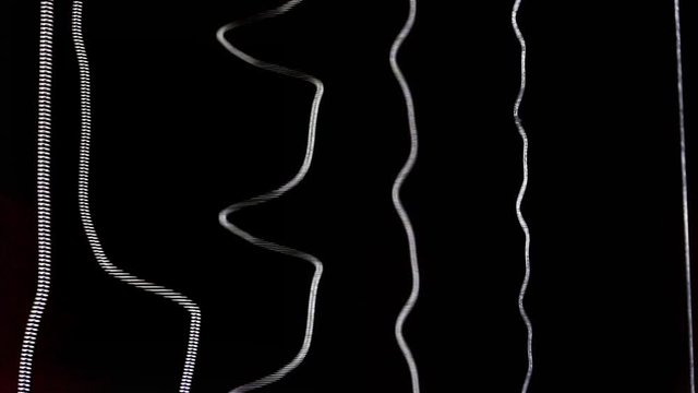 Acoustic guitar strings vibrating while playing music creating amazing patterns and soundwaves while strumming chords and single notes heavily on black background of the soundhole close up detail shot