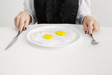 We are what we eat. Close up of woman's eating fried eggs of plastic, eco concept. There is so much polymers then we're just made of it. Environmental disaster, fashion, beauty. Loosing organic world.