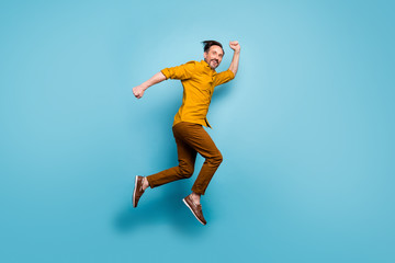 Fototapeta na wymiar Full body profile side photo of cheerful crazy man jump run after spring time black friday sales feel rejoice emotions wear casual style clothes isolated over blue color background