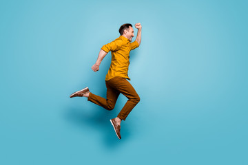 Fototapeta na wymiar Full size profile side photo of cheerful positive man jump run after spring time sales wear casual style outfit sneakers isolated over blue color background