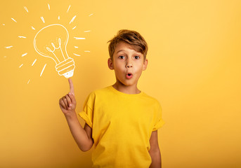 Emotional Child have a big idea. Surprised and amazed face expression. Yellow background © alphaspirit