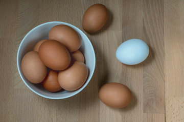 several fresh chicken eggs in a ceramic cup on a wooden background. Healthy eating concept