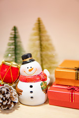 Christmas decoration concept. Smiley snowman toy, gift box, pine cone and mini Christmas tree on the table. Decorative objects for Xmas and New Year holiday. Ornament for Festive season celebration