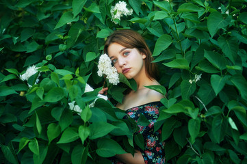 Portrait of a young girl in the Park on a background of greenery . The girl with the lilac .