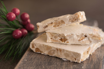 Turron, typical Christmas sweet in Spain. Almond nougat on dark wooden background with Christmas decoration