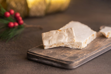 Turron, typical Christmas sweet in Spain. Almond nougat on dark wooden background with Christmas decoration