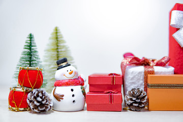 Christmas decoration concept. Smiley snowman toy, gift box, pine cone and mini Christmas tree on the table. Decorative objects for Xmas and New Year holiday. Ornament for Festive season celebration