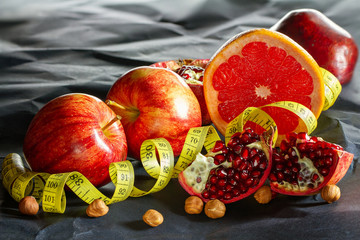 Red juicy apples, pieces of pomegranate and nuts close-up on a dark background.