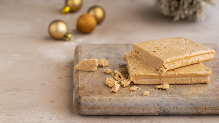 Turron, typical Christmas sweet in Spain. Almond nougat on wooden background with Christmas decoration .