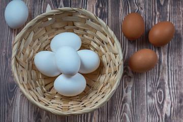 several fresh chicken eggs in a straw basket on a wooden background. Healthy eating concept