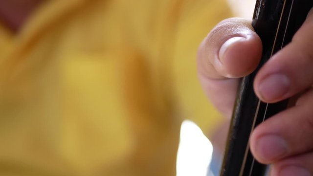 Close up a musician's hand playing Salor, two or three-string spike fiddle used in the Lanna region or in the North of Thailand
