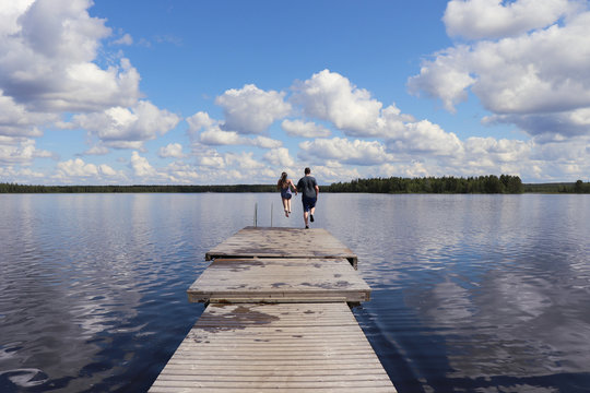 Two teens racing to the end of a dock at Lake Ranuanjarvi in Finland