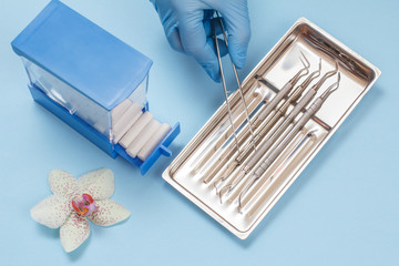 Dentist's hand with set of metal dental instruments for teeth dental care