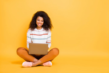 Portrait of her she nice attractive lovely cheerful cheery wavy-haired girl sitting in lotus pose typing working studying remotely isolated on bright vivid shine vibrant yellow color background - obrazy, fototapety, plakaty