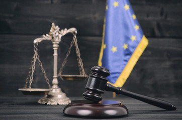 Scales of Justice, Judge Gavel and Flag of the European Union on a wooden background.