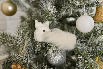 Beautifully decorated Christmas tree. White sleeping fox Christmas toy.
