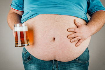 A man with a fat belly holding a glass of beer. On gray background&
