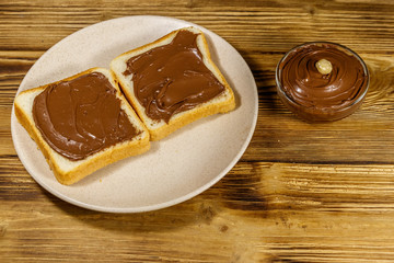 Two slices of bread with delicious chocolate hazelnut spread on wooden table