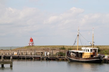 Kleines traditionelles Fischerboot im Hafenmit rotem Leuchtfeuer - 307342011