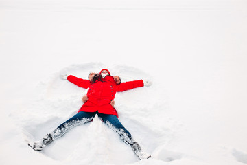 Snow angel made by a woman in the snow. Top flat overhead view