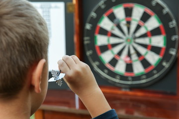  child aiming a dart at a darts board