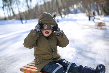 Fototapeta na wymiar Boy sledding on the street in the snowy winter in the mountains.