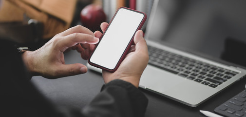 Cropped shot of young professional businessman working on his project while using smartphone in dark modern office