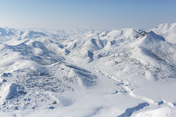 Fototapeta na wymiar Top view of a snowy valley, mountains and hills. Beautiful aerial landscape. Traveling and hiking in the far north of Russia. Location place: Meingypilgyn Range, Chukotka, Siberia, Russian Far East.