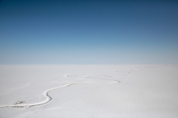 Amazing Arctic aerial landscape. Top view of the endless snow-covered tundra and the Avtatkuul River. Travel to the far North of Russia. Location place: Chukotka, Siberia, Russian Far East.