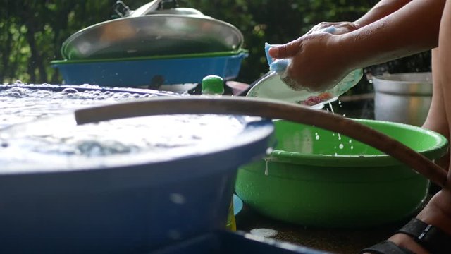 Washing plates outside of the house, a typical rural-Thai way of washing / cleaning kitchenware at home