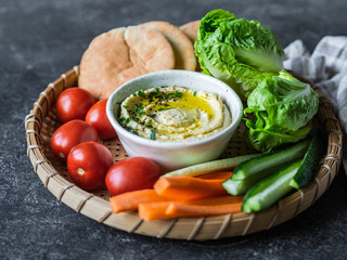 Homemade traditional spread hummus dip served with fresh vegetable , pita and herbs in tray