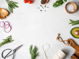 Fresh raw greens, vegetables, spices and kitchenwere frame on grey background. top view,