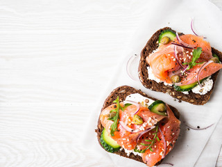 Healthy toasts with rye bread with cream cheese, salmon, fresh cucumber, capers, sesame seeds,...