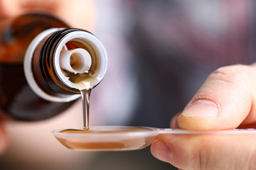 Sick man holding in hands vial with syrup close-up