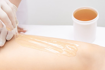 Hair removal at spa luxury studio. Woman legs wax with shugaring. Hot sugar. Product waxing bowl. Salon jar