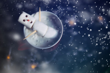 Cute little snowman made from marshmallows bathing in a mug with hot chocolate 
