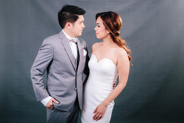 Young asian groom and bride posing and smiling in studio for pre-wedding shot