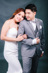Young asian groom and bride posing and smiling in studio for pre-wedding shot