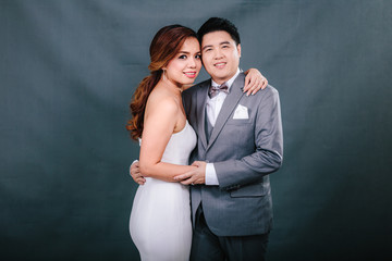 Young asian groom and bride posing and smiling in studio for pre-wedding shot