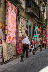 Old man walking in a street, multicolored fabric in a Granada street, Andalusia, Spain.