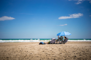 Couple under a umbrella, on a spanish beach, El Campello, Muchavista Playa, Alicante, Spain