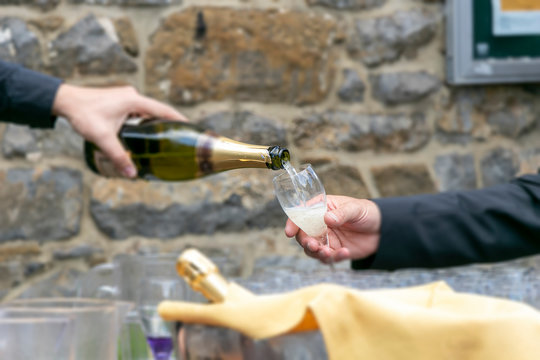close up of a man hand pouring champagne in the glass for celebrated a party outdoor, blurred image.  