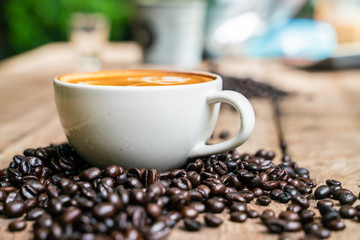Latte art coffee cup with coffee bean on wooden background
