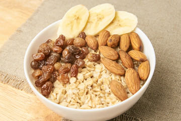 Oatmeal breakfast bowl. Organic healthy food with candied fruit raisins, nuts, banana