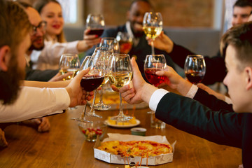 Happy co-workers celebrating while company party and corporate event. Young caucasian people in business attire cheering, laughting. Concept of office culture, teamwork, friendship, holidays, weekend.