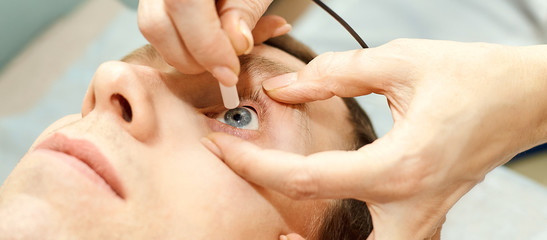 ophthalmologist doctor in exam optician laboratory with male patient. Men eye care medical diagnostic. Eyelid treatment