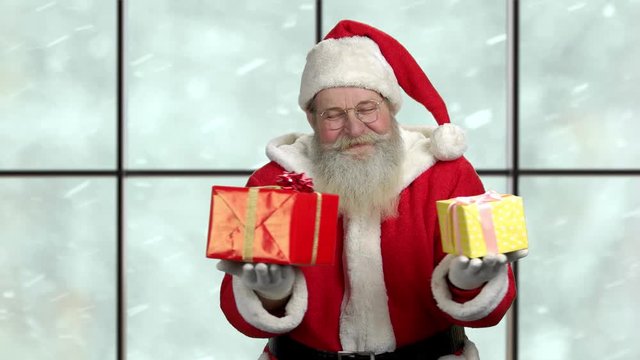 Cute Christmas Santa Claus with git boxes. Old happy Santa Claus on checkered window background. Magic Christmas atmoshpere.