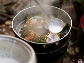 Filling coconut milk into Thai food wrapped in banana leaves 