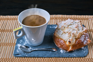 pao de deus, typical Portuguese dessert and a coffee with a spoon ver a blackboard and a wood table