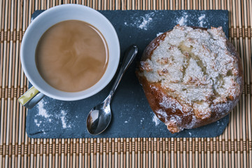 pao de deus, typical Portuguese dessert and a coffee with a spoon ver a blackboard and a wood table